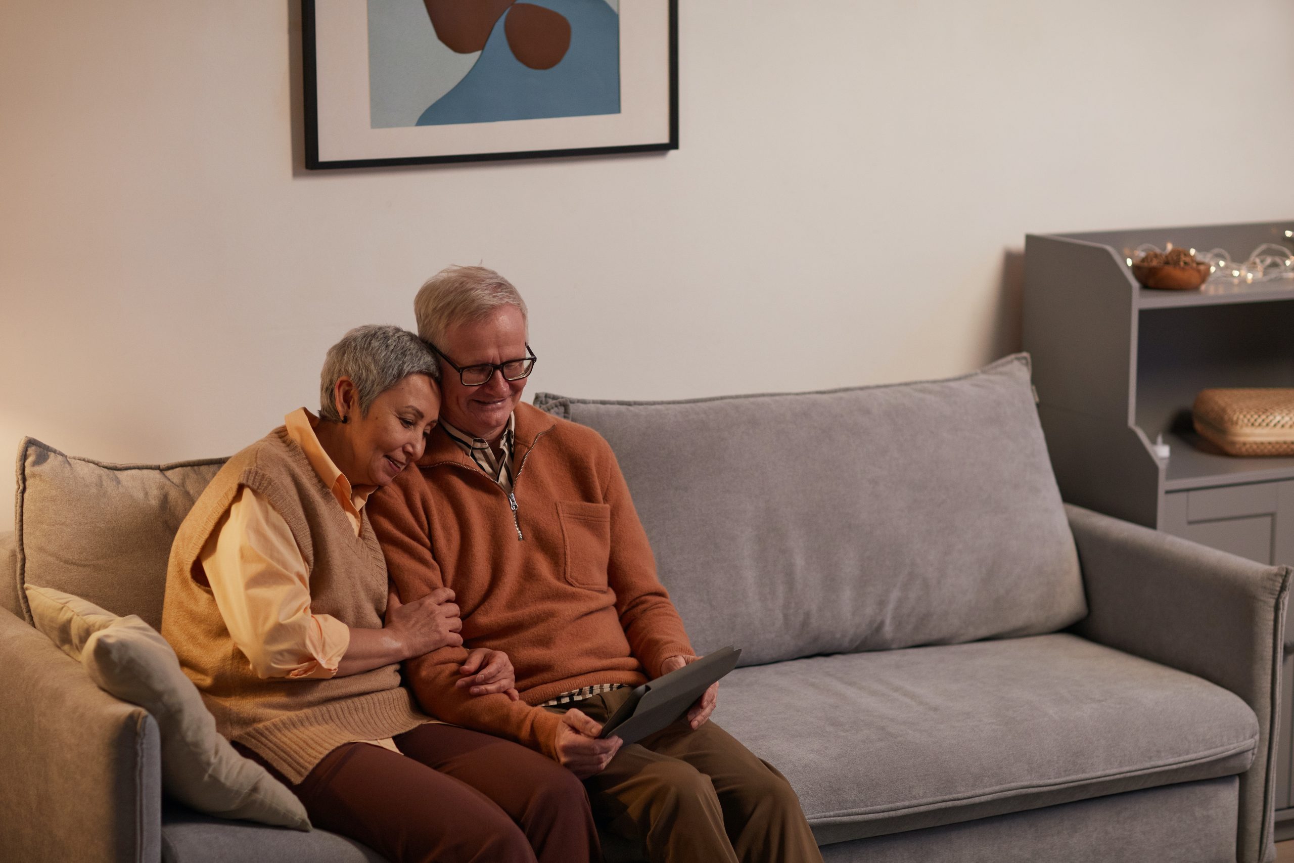 older couple sitting on the couch with tablet